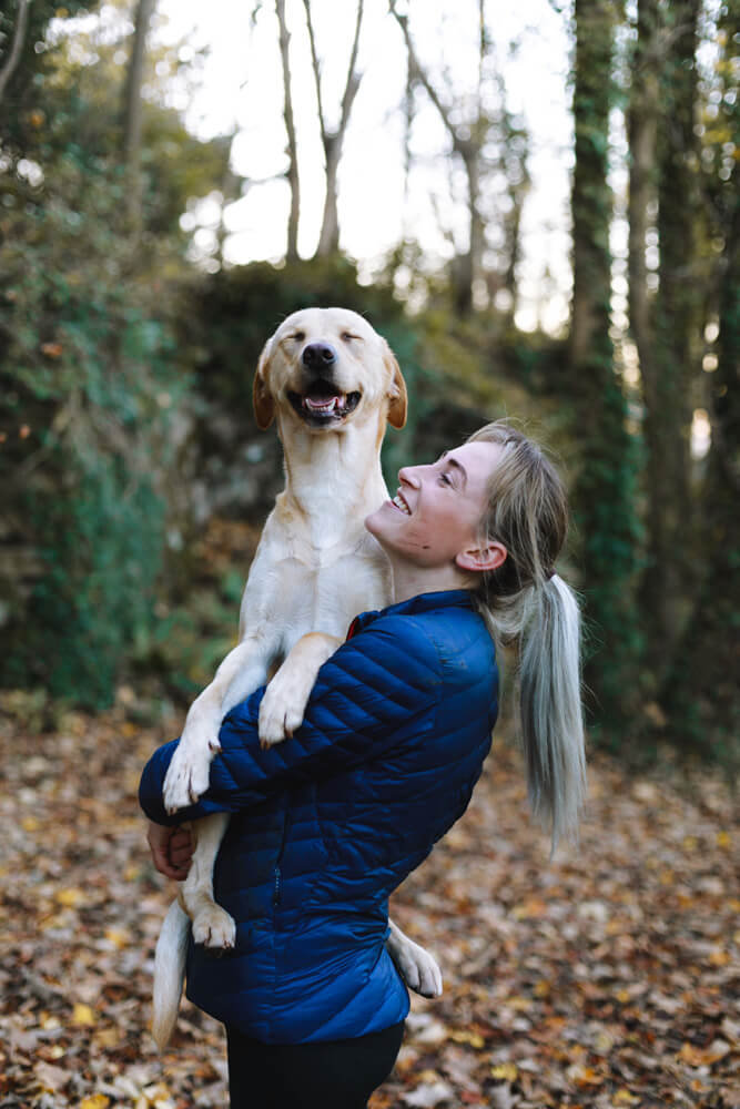 smiling white lab being hugged by a woman in the forest - Pawsitive Care Animal Hospital, Manassas, Virginia veterinarian